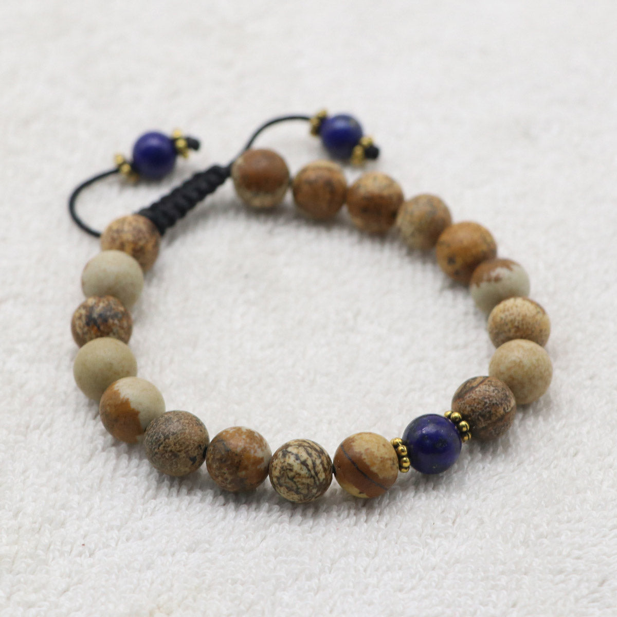 A beaded bracelet made of natural Jasper stone beads, accented with two dark blue lapis lazuli beads and small gold spacer rings.
