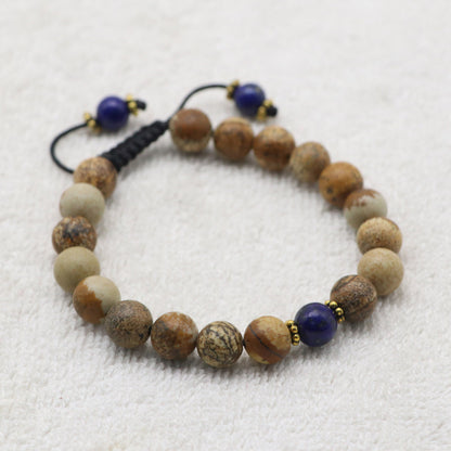 A beaded bracelet made of natural Jasper stone beads, accented with two dark blue lapis lazuli beads and small gold spacer rings.